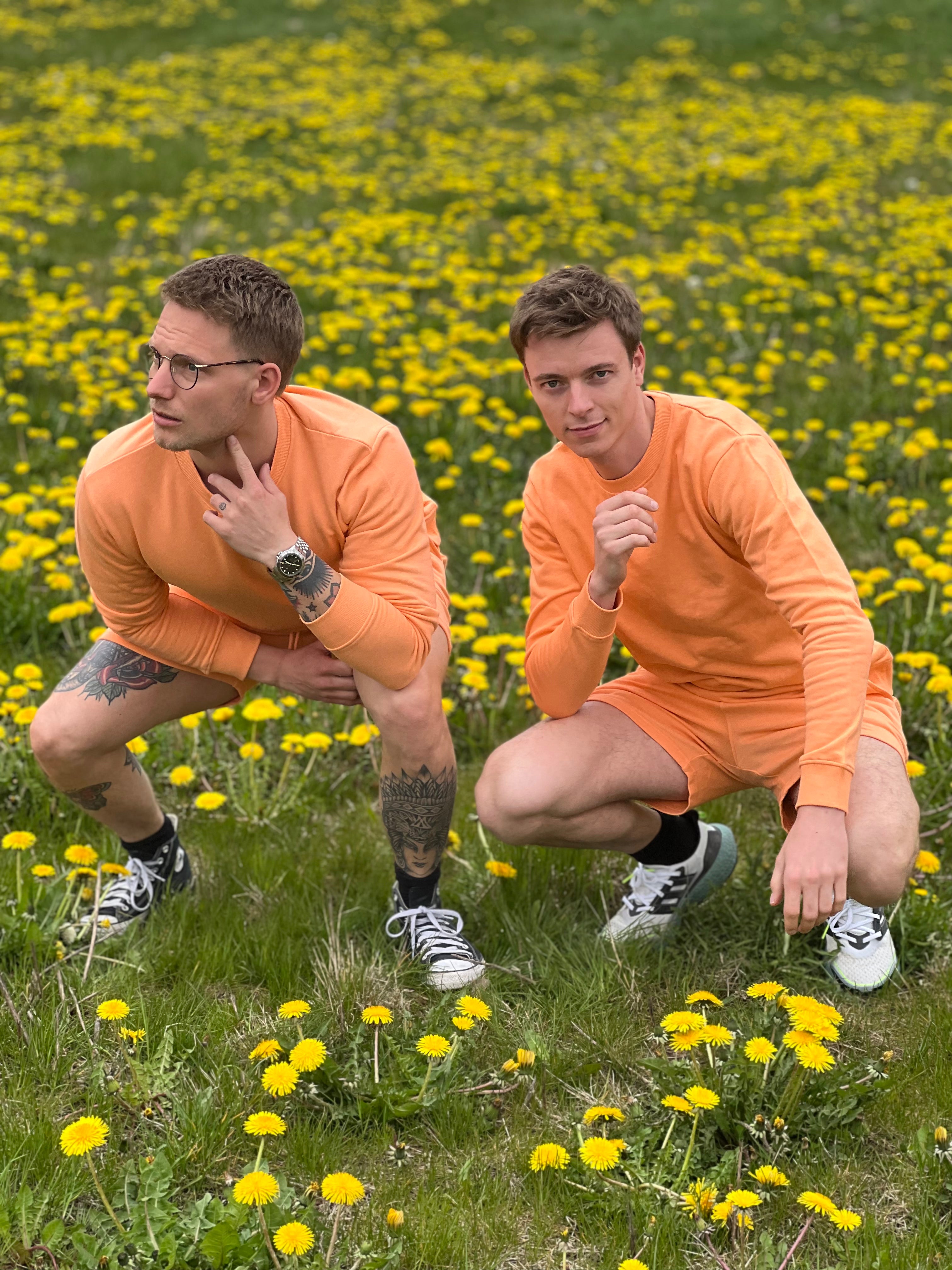 To mænd poserer sammen i et ferskenfarvet sommersæt.